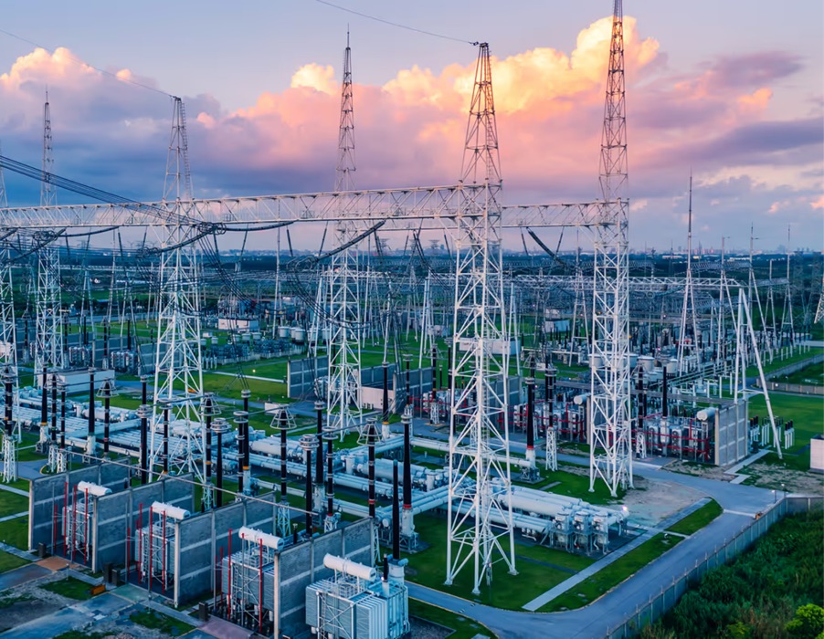 Transmission pylons and a substation at dusk.